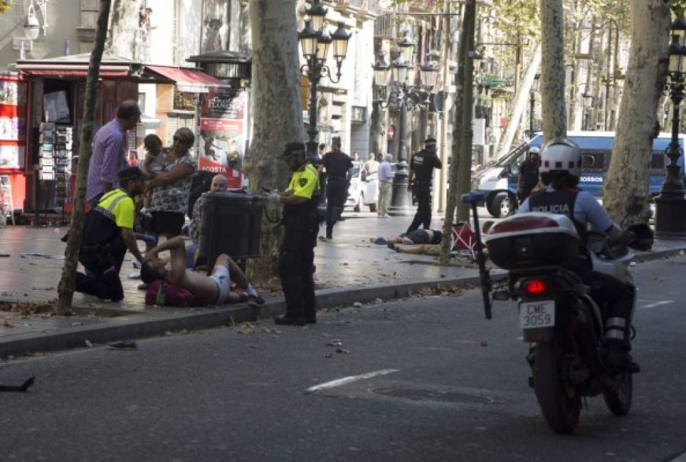 GRA186. BARCELONA, 17/08/2017.- Efectivos policiales atienden a una de las víctimas de un atropello masivo de una furgoneta que ha arrollado esta tarde a varias personas que paseaban por las Ramblas de Barcelona. Los Mossos d'Esquadra y los equipos de emergencias sanitarias han desplegado un amplio dispositivo en esta zona, en el centro turístico de la capital catalana, frecuentada a diario por miles de turistas, que ha quedado acordonada. EFE/David Armengou