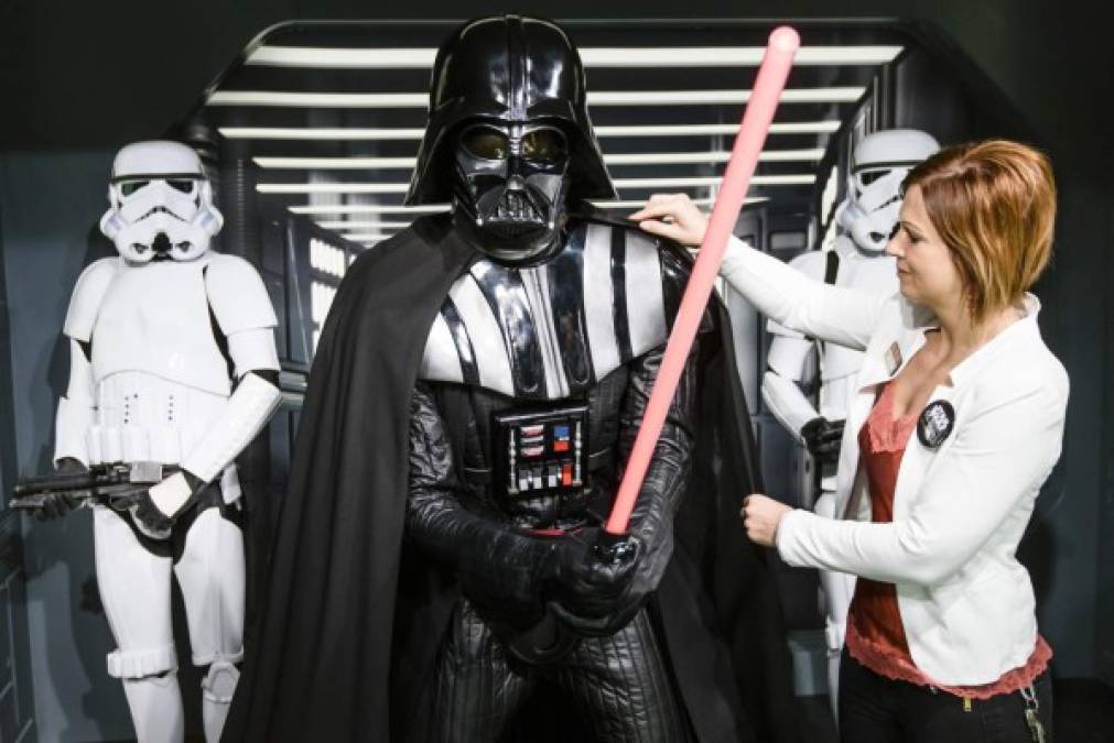 Una empleada posa con la figura de cera de Darth Vader.
