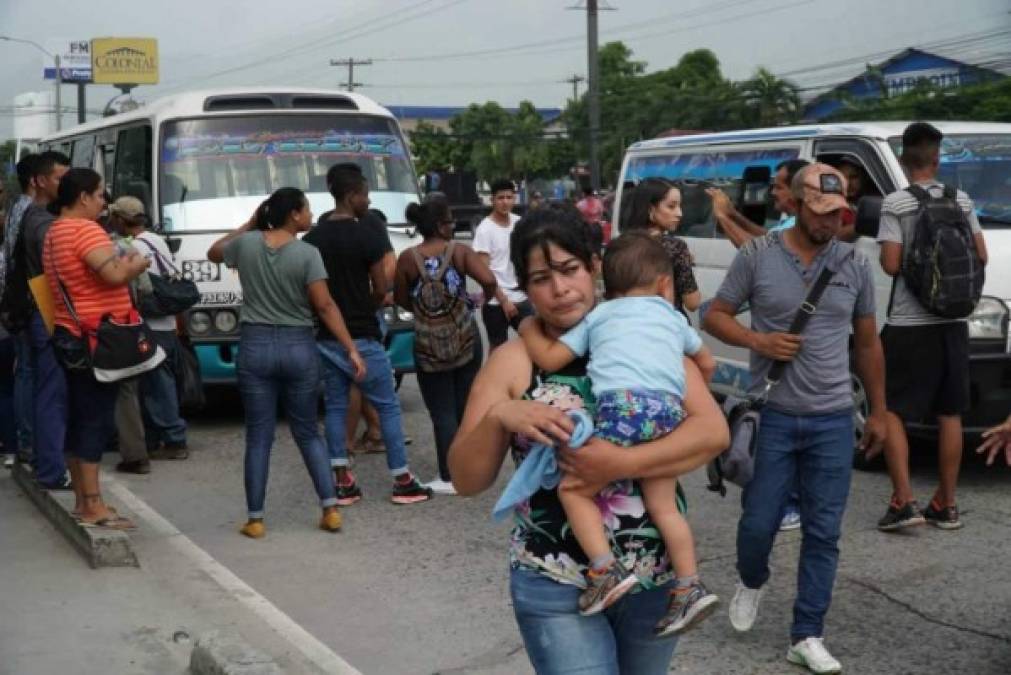 Una mujer lleva a su hijo en brazos después de que no encontrara un medio de transporte para desplazarse hacia su lugar de destino.