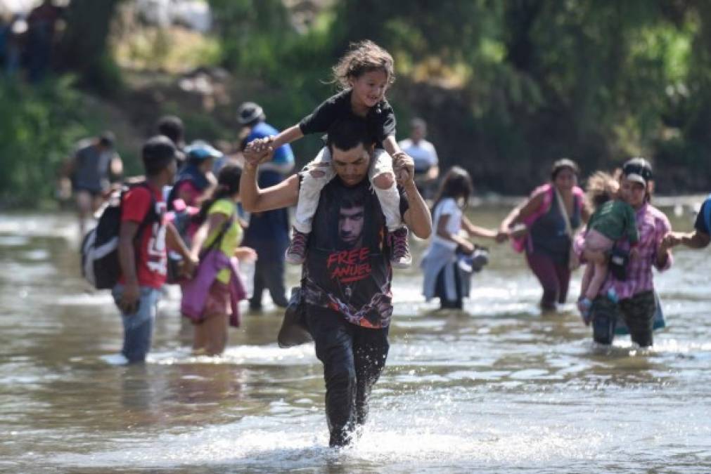 TOPSHOT - Central American migrants - mostly Hondurans, travelling on caravan to the US- cross the Suichate River, the natural border between Tecum Uman, Guatemala and Ciudad Hidalgo, Mexico, on January 20, 2020. - Hundreds of Central Americans from a new migrant caravan tried to enter Mexico by force Monday by crossing the river that divides the country from Guatemala, prompting the National Guard to fire tear gas, an AFP correspondent said. (Photo by Johan ORDONEZ / AFP)