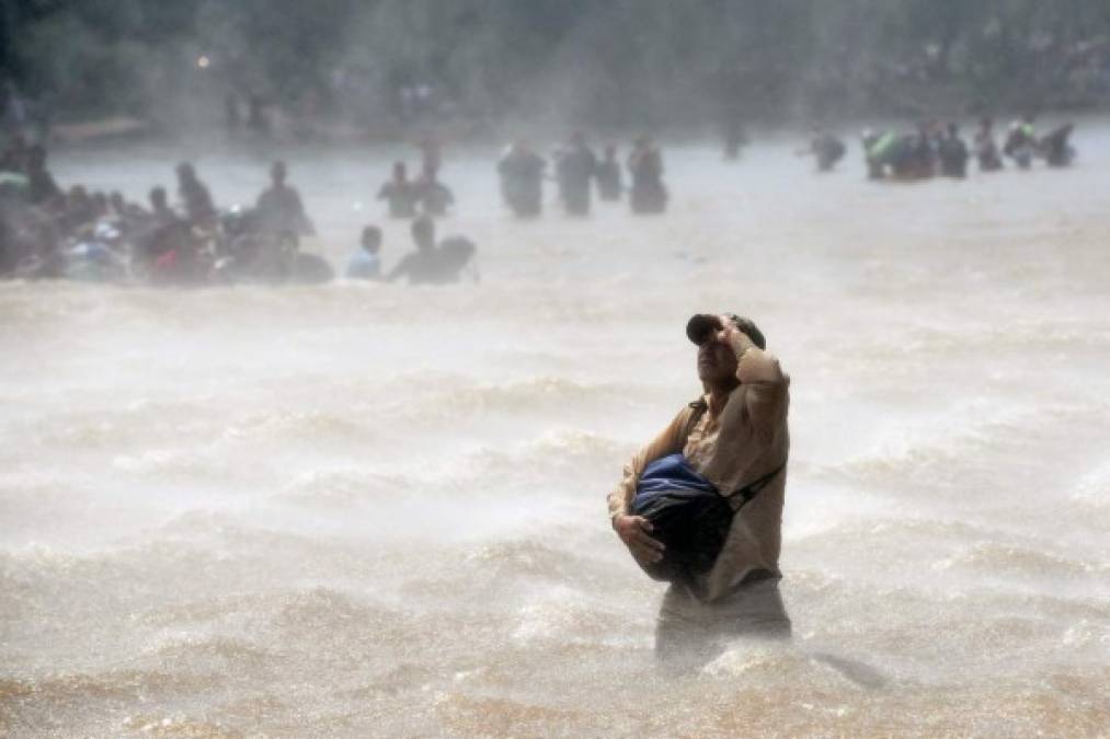 -- AFP PICTURES OF THE YEAR 2018 --<br/><br/>Migrants cross the Suchiate River from Tecun Uman in Guatemala to Ciudad Hidalgo in Mexico, after a security fence on the international bridge was reinforced to prevent them from passing through, on October 29, 2018. - A new group of Honduran migrants is trying to reach and cross the Guatemalan border into Mexico in the hope of eventually realizing the 'American dream' and reaching the United States. (Photo by Johan ORDONEZ / AFP)