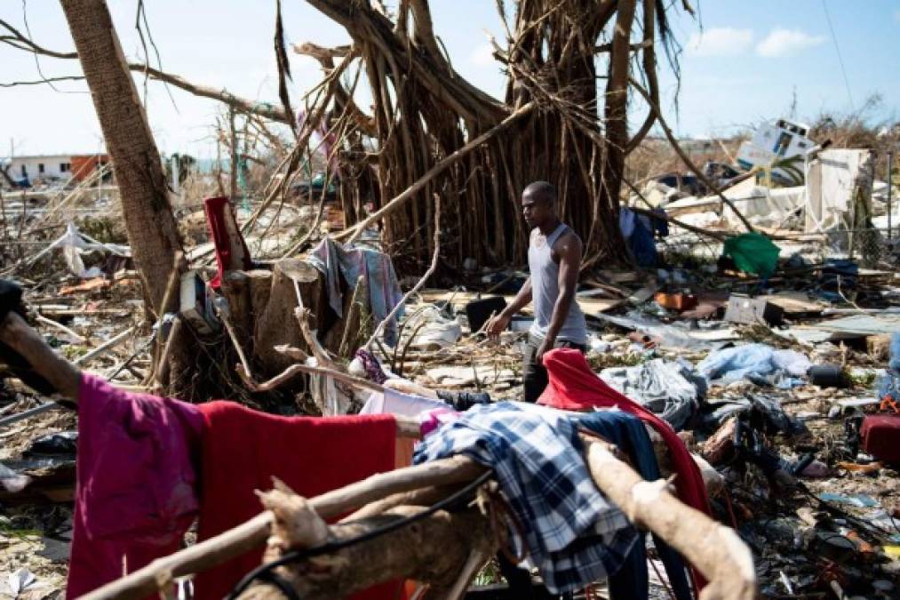 A man walks past damages caused by Hurricane Dorian on September 5, 2019, in Marsh Harbour, Great Abaco Island in the Bahamas. - Hurricane Dorian lashed the Carolinas with driving rain and fierce winds as it neared the US east coast Thursday after devastating the Bahamas and killing at least 20 people. (Photo by Brendan Smialowski / AFP)