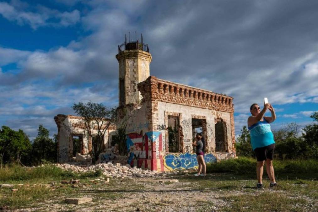 Turistas le toman una foto a un edificio colapsado.