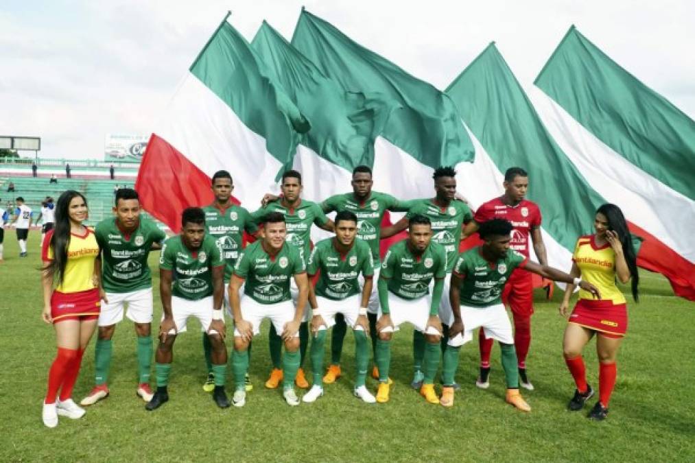 El once titular del Marathón, acompañado por dos bellas chicas y grandes banderas en el fondo.