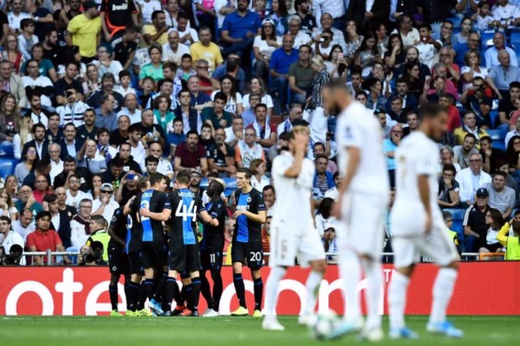 La celebración de los jugadores del Brujas, mientras los del Real Madrid, cabizbajos.