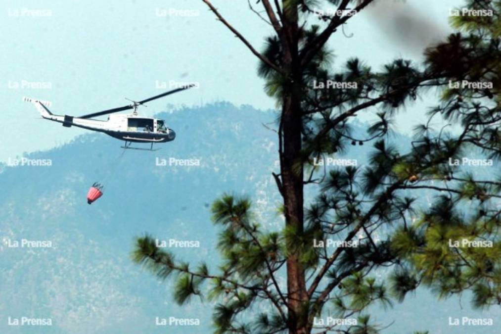 Un helicóptero de la Fuerza Aérea deja caer agua sobre parte del bosque quemado en Tegucigalpa.