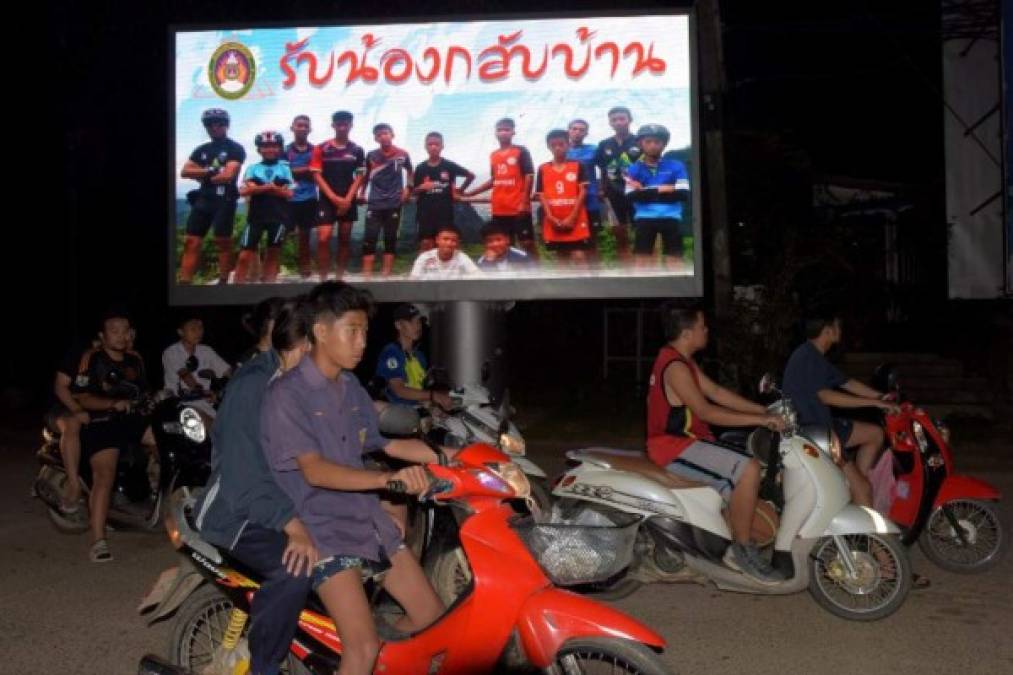 Un rótulo muestra una fotografía de los miembros del equipo tailandés y su entrenador con el mensaje 'bienvenidos a casa hermanos'.