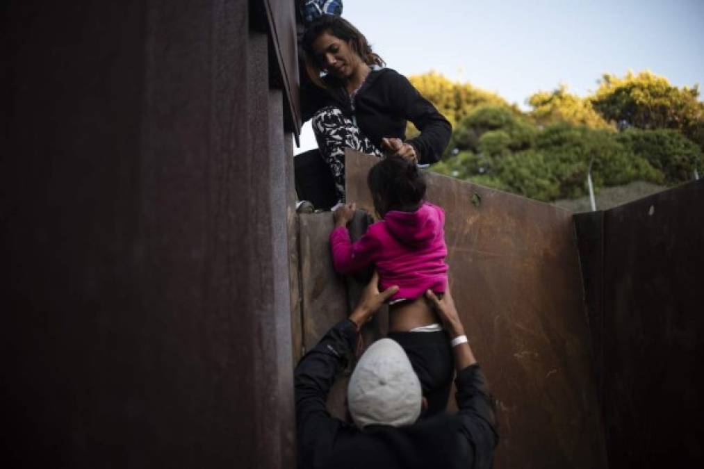 TOPSHOT - Central American migrants who have been travelling in a caravan hoping to get to the United States, climb the metal barrier separating Mexico and the US to cross from Playas de Tijuana in Mexico into the United States, on December 2, 2018. - Thousands of Central American migrants, mostly Hondurans, have trekked for over a month in the hopes of reaching the United States. (Photo by PEDRO PARDO / AFP)