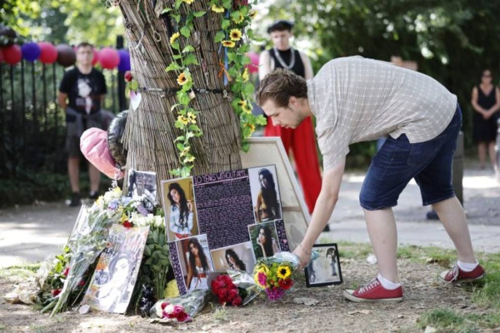 Varios fans se reúnen en un santuario temporal cerca de la antigua casa de la cantante británica Amy Winehouse en el norte de Londres, el 23 de julio de 2021 para conmemorar el décimo aniversario de su muerte.