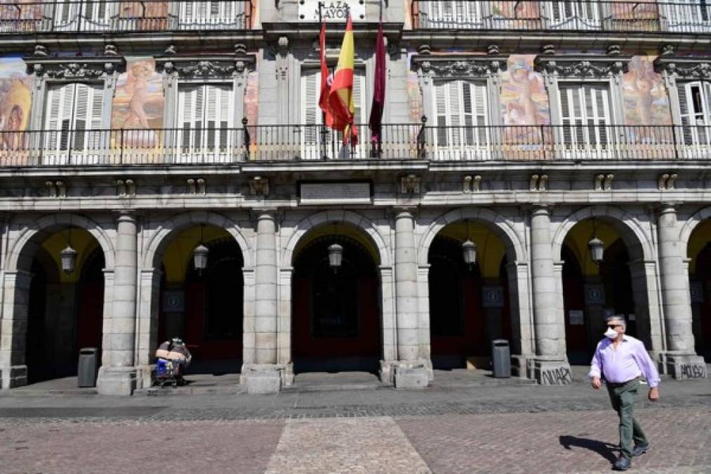 El 14 de marzo de 2020, un hombre que llevaba una máscara protectora camina por la abarrotada Plaza Mayor, en el centro de Madrid.