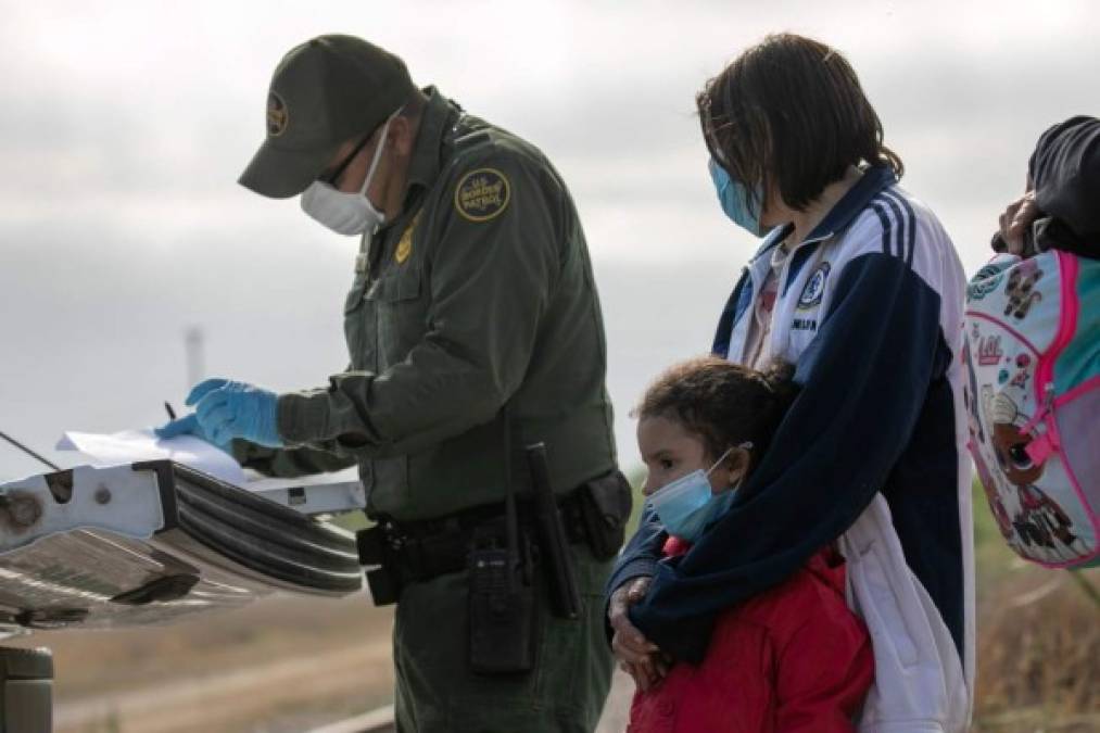 PENITAS, TEXAS - MARCH 27: A group of people climbs over a fence as they walk with a U.S. Border Patrol agent after being caught crossing the border from Mexico on March 27, 2021 in Penitas, Texas. The group made up of individuals from Mexico, El Salvador, Honduras, and Guatemala ran from the agents before being caught. Joe Raedle/Getty Images/AFP<br/><br/>== FOR NEWSPAPERS, INTERNET, TELCOS & TELEVISION USE ONLY ==<br/><br/>