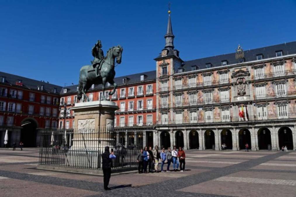 Un grupo de personas posa hoy para una foto en la Plaza Mayor, que suele estar abarrotada, en el centro de Madrid, pero hoy está desolada.