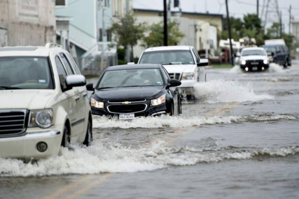 Una fila de vehículos recorre las inundadas calles de la ciudad de Texas City.