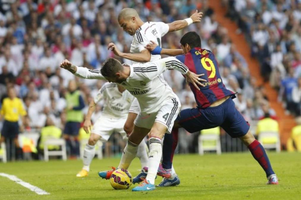 El defensa portugués del Real Madrid, Pepe y su compañero Sergio Ramos, luchan un balón con el delantero uruguayo del FC Barcelona, Luis Suárez.
