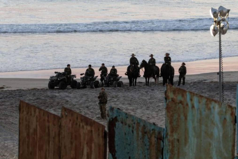 US Border Patrol and Defense Department officers guard near the border fence with Mexico as Central American migrants moving in a caravan towards the United States arrive in the area, as seen from Playas de Tijuana, in Mexico, on November 16, 2018. (Photo by Guillermo Arias / AFP)