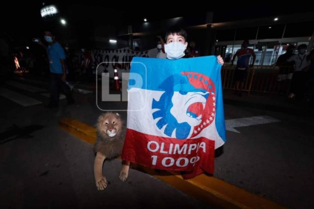 Un niño aficionado del Olimpia posando con su bandera y un peluche del León.