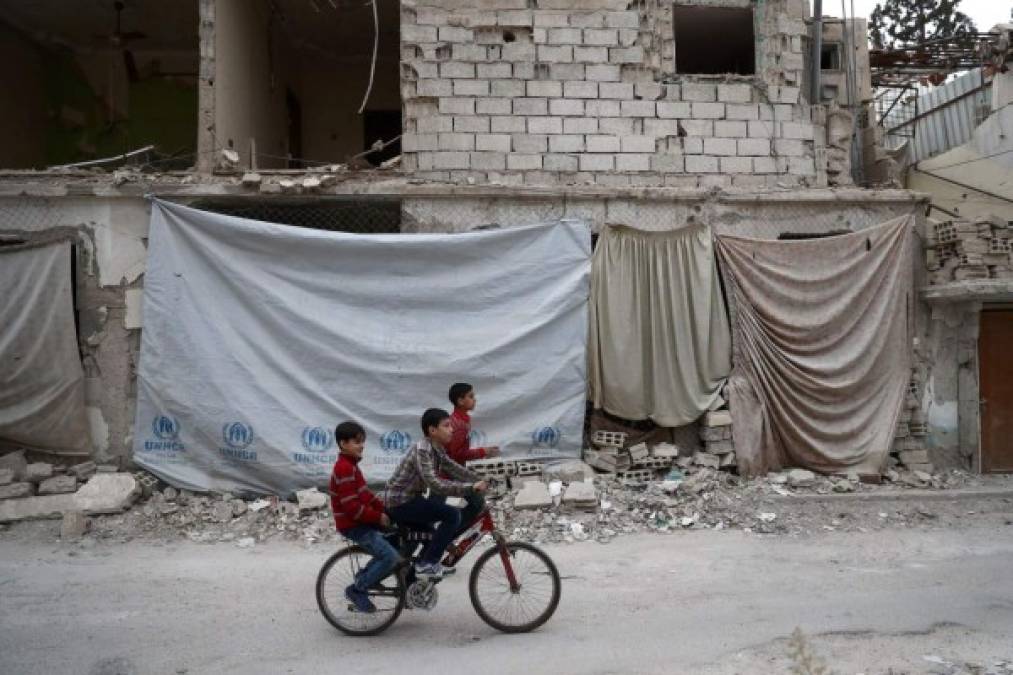 SIRIA. Un paseo entre las ruinas. Niños sirios juegan en la ciudad de Douma, bombardeada por el régimen de Asad tras ser tomada por los rebeldes. Foto: AFP/Abd Doumany