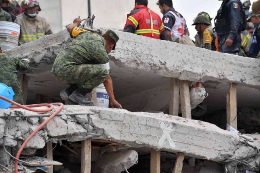 A soldier searches for survivors in a flattened building in Mexico City on September 20, 2017 a day after a strong quake hit central Mexico.<br/>A powerful 7.1 earthquake shook Mexico City on Tuesday, causing panic among the megalopolis' 20 million inhabitants on the 32nd anniversary of a devastating 1985 quake. / AFP PHOTO / Yuri CORTEZ