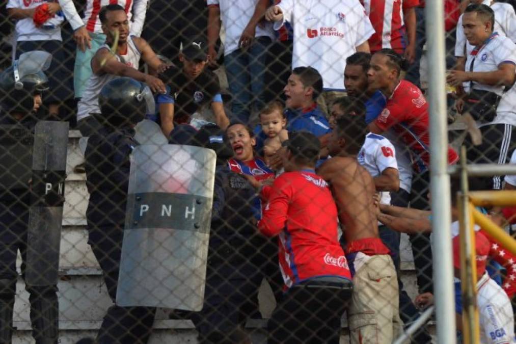 Una madre aficionada del Olimpia sostiene a su hijo en brazos durante los disturbios con la policía.