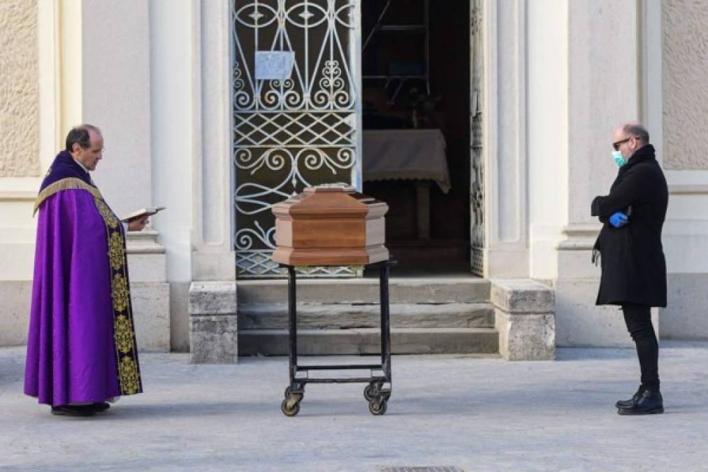 Un sacerdote lee la biblia en un funeral de una persona fallecida por coronavirus COVID-19 en Italia. Autoridades solo permiten a un familiar en los funerales. Las imágenes muestran que los familiares en luto tienen que estar a más de 1 metro de distancia. Fotos: AFP