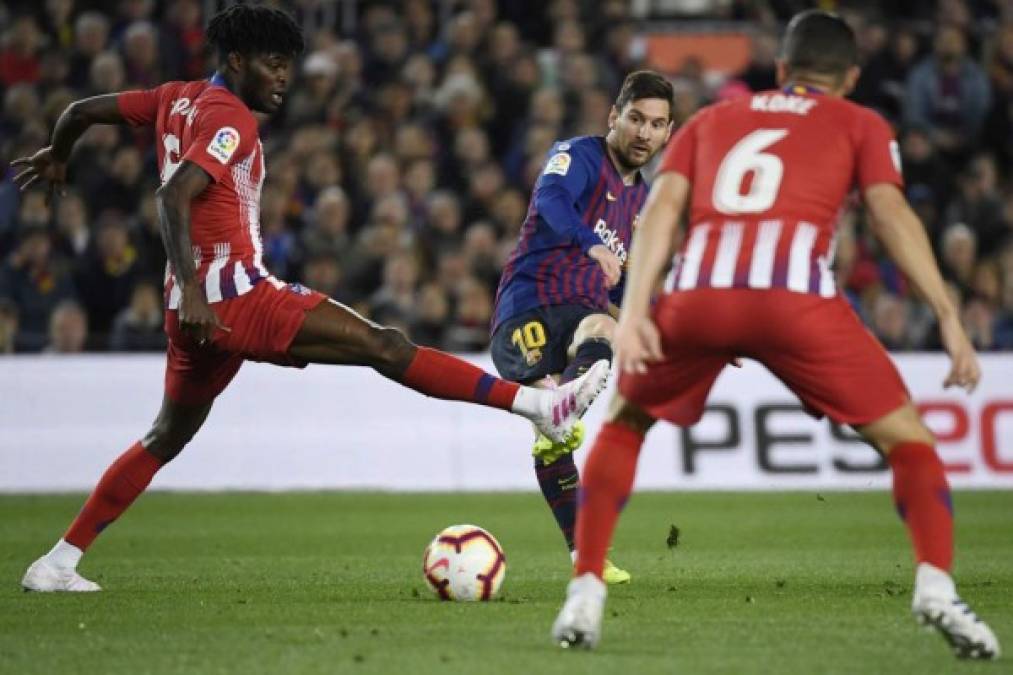 Messi intenta pasar el balón ante la marca del ghanés Thomas Partey, mientras Koke observa la acción. Foto AFP