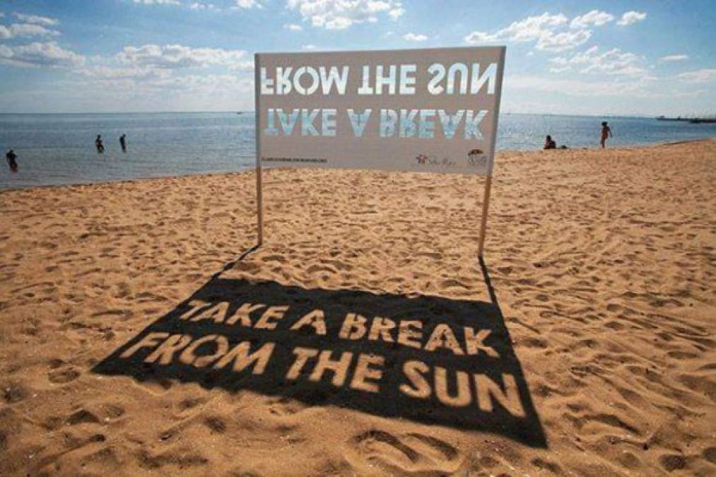 Este anuncio, que a primera vista se ve al revés en plena playa sirve en realidad para frenar los rayos del sol y dar sombra a los veraneantes.