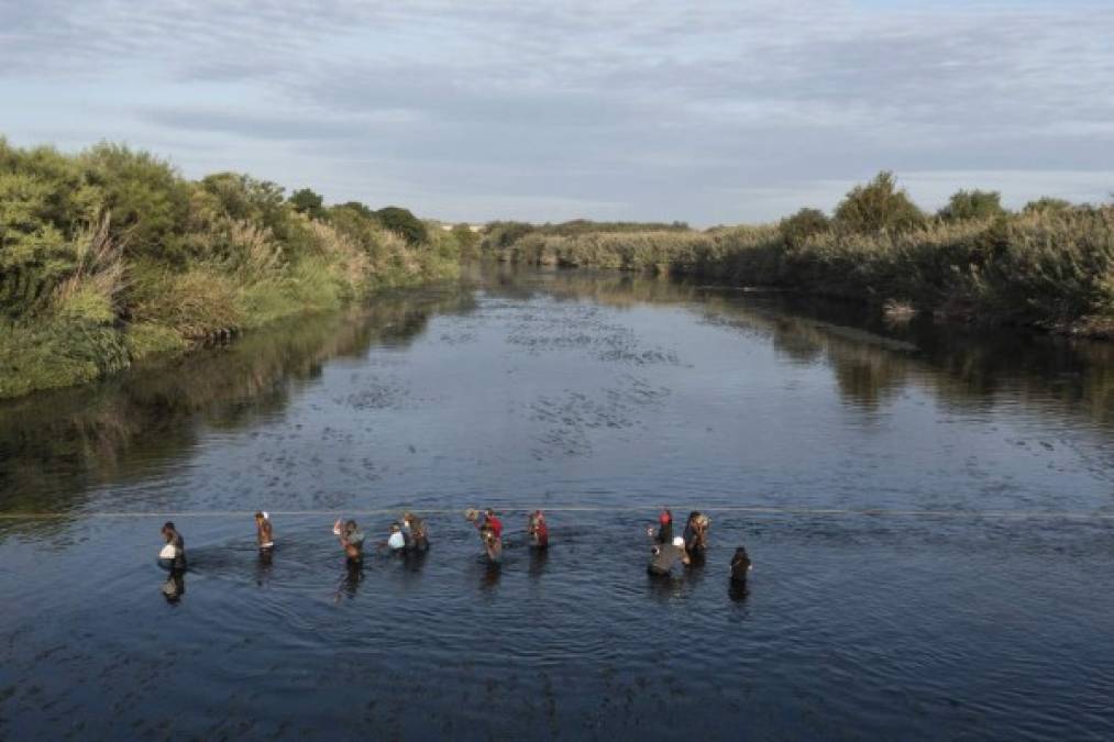 In this aerial view Haitian migrants cross the Rio Grande river to get food and water in Mexico, as seen from Ciudad Acuna, Coahuila state, Mexico on September 22, 2021. - Clinging to ropes, some carrying children on their shoulders, Haitian migrants stranded at the US border cross the Rio Grande back into Mexico in search of food, water or medical treatment. (Photo by PEDRO PARDO / AFP)