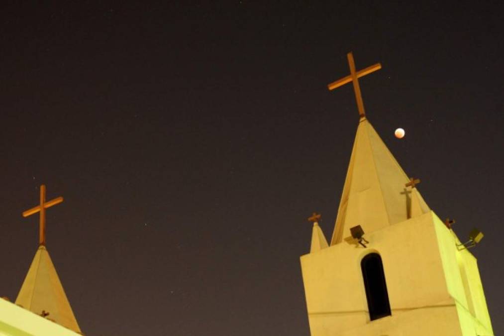 Una cruz religiosa es vista junto a la Luna durante un eclipse total lunar, llamado 'lunas de sangre', el 8 de octubre de 2014 en Los Angeles, California. AFP