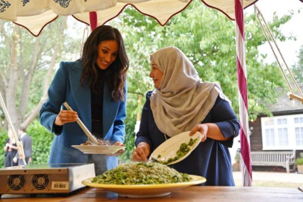 Durante el evento Meghan ayudó a preparar la comida, mientras era observada por su esposo y su madre.<br/>