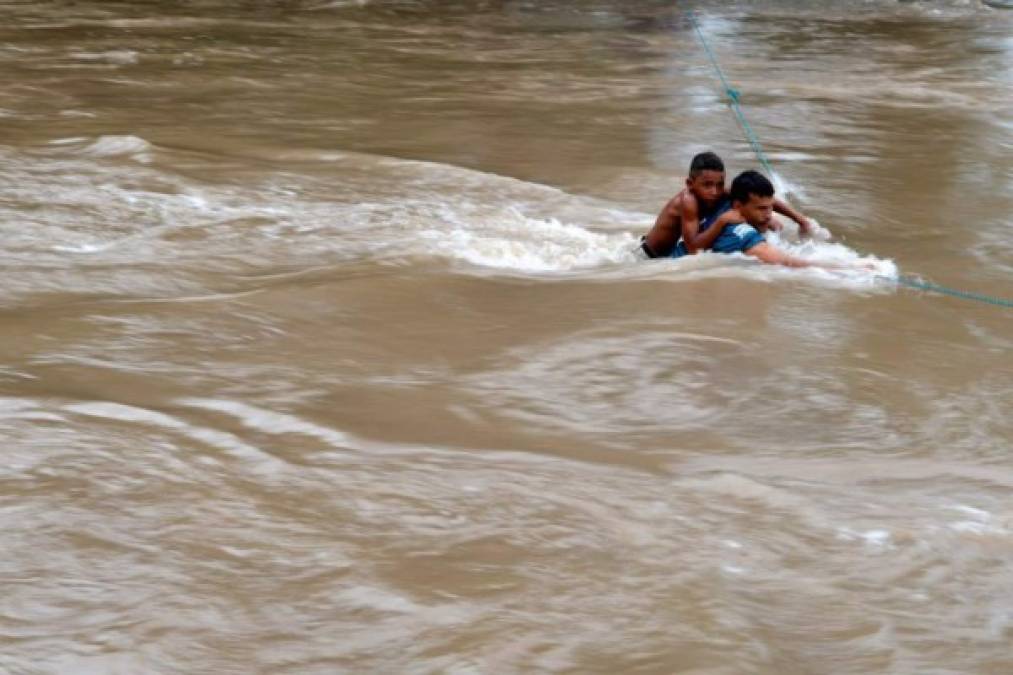 Honduran migrants attempt to cross the border Goascoran River to enter illegally to El Salvador, in Goascoran, Honduras on October 18, 2018. - US President Donald Trump threatened Thursday to send the military to close its southern border if Mexico fails to stem the 'onslaught' of migrants from Central America, in a series of tweets that blamed Democrats ahead of the midterm elections. (Photo by MARVIN RECINOS / AFP)