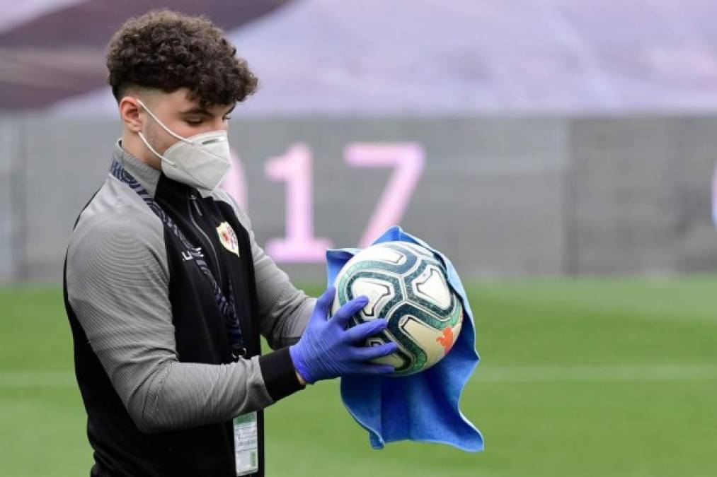 Un recogebalones desinfecta una pelota durante un momento del partido.