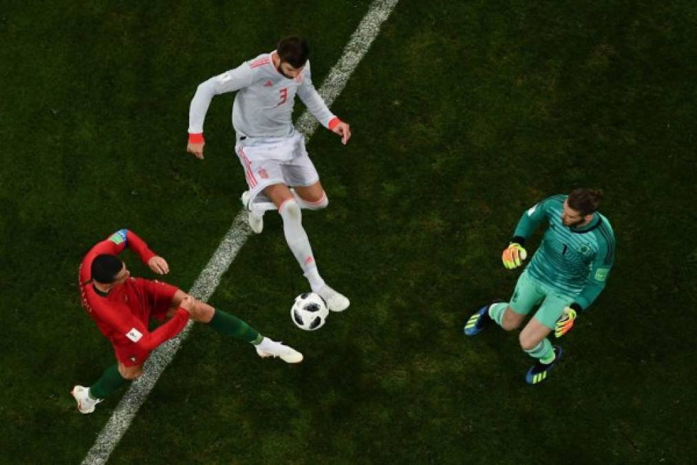 Cristiano Ronaldo intenta anotar ante la marca de Piqué y De Gea. Foto AFP