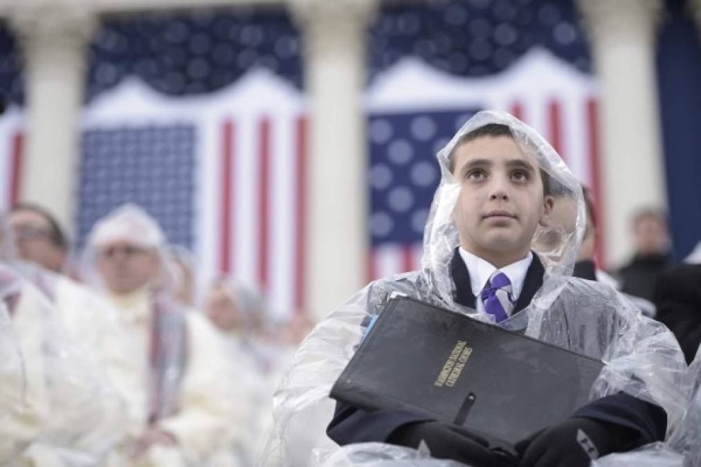 Los miembros del coro que cantó durante la ceremonia se protegen de la lluvia que cayó en Washington esta mañana.