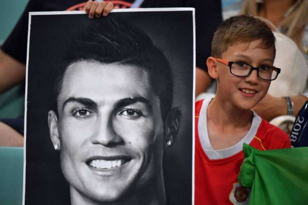 Un niño, con la camiseta del Manchester United, posa con una fotografía de Cristiano Ronaldo en las gradas. Foto AFP