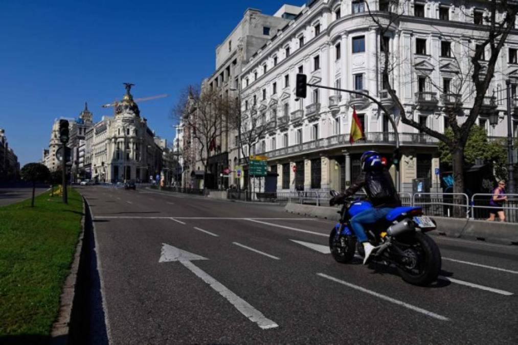 Un motociclista pasa hoy por la Plaza Cibeles mientras las avenidas permanecen vacías en Madrid después de que las autoridades regionales ordenaron que se cerraran todas las tiendas de la región desde hoy hasta el 26 de marzo, a excepción de las que venden alimentos, químicos y estaciones de servicio, para frenar propagación del coronavirus.