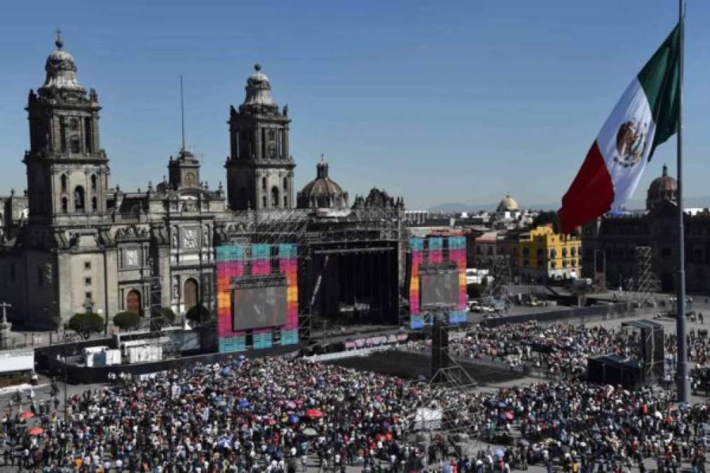 La gente en la plaza del Zócalo, en la Ciudad de México, mira en pantalla gigante la ceremonia de inauguración del nuevo presidente de México, Andrés Manuel López Obrador (AMLO) que se celebra hoy en el Congreso de la Unión.