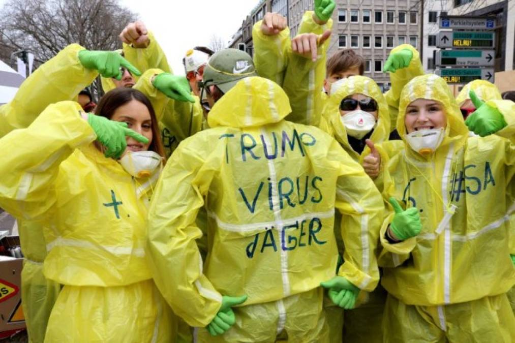 Vestidos con trajes protectores y guantes, varios manifestantes se protegen del contagio del 'virus Trump'.