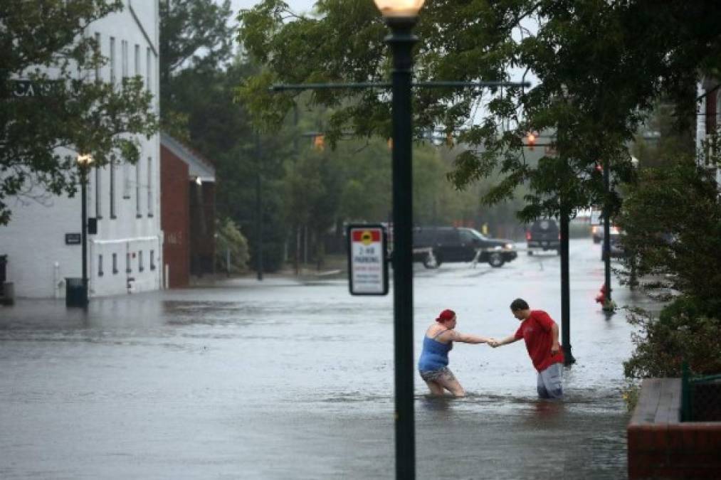 NEW BERN, NC - SEPTEMBER 13: Shianne Coleman (L) gets a hand from friend Austin Gremmel as they walk in flooded streets as the Neuse River begins to flood its banks during Hurricane Florence September 13, 2018 in New Bern, North Carolina. Coastal cities in North Carolina, South Carolina and Virginia are under evacuation orders as the Category 2 hurricane approaches the United States. Chip Somodevilla/Getty Images/AFP
