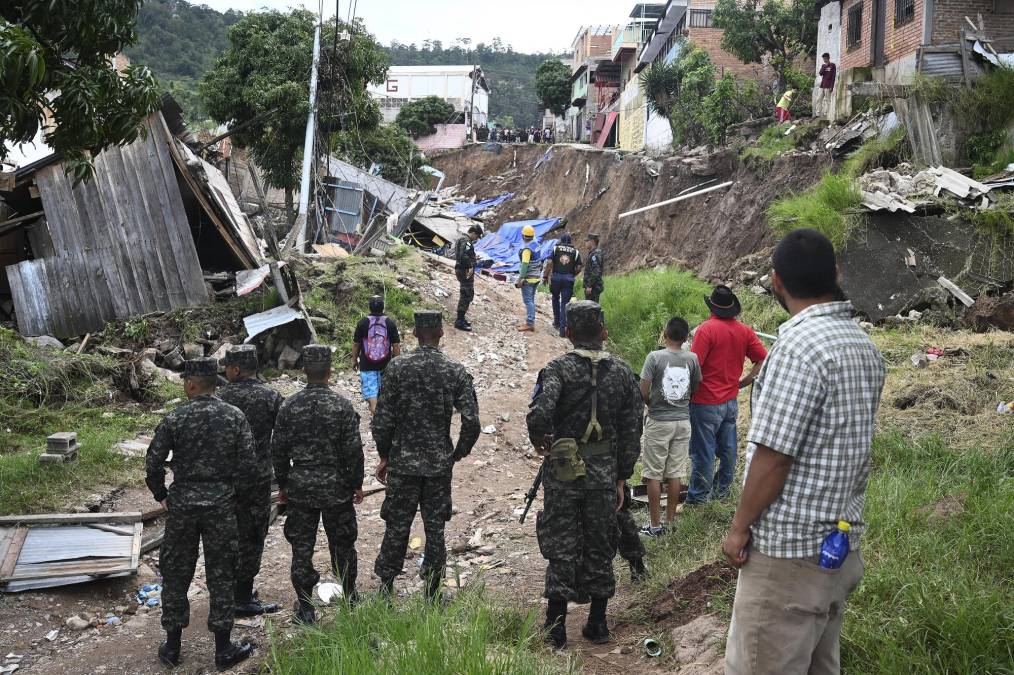 Soldiers and residents look at the damage caused in Colonia Guillen, a neighbourhood northwest of Tegucigalpa that was declared uninhabitable by authorities due to landslides and mudslides caused by rains on September 16, 2022. (Photo by Orlando SIERRA / AFP)