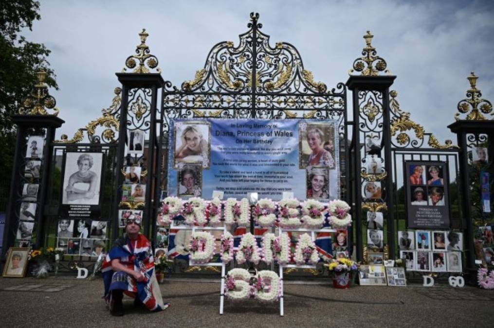 John Loughrey, un admirador de la princesa de Gales, posa junto a una ofrenda floral y fotografías pegadas a las puertas del Palacio de Kensington para celebrar lo que habría sido el 60 cumpleaños de la princesa Diana.