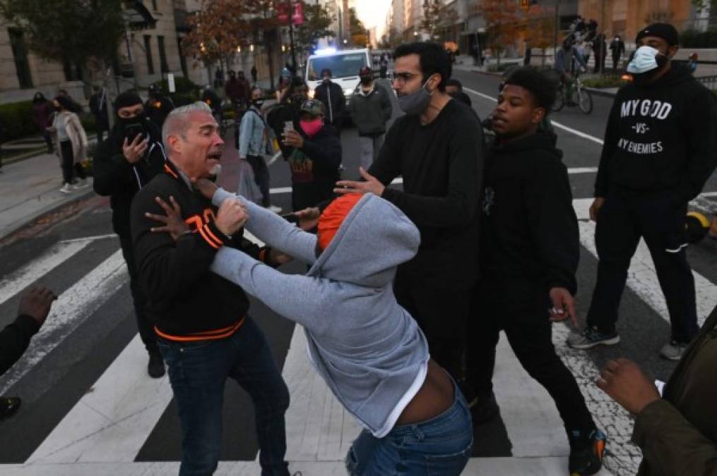 A supporter of US President Donald Trump (L) is attacked by anti-Trump demonstrators in Black Lives Matter Plaza in Washington, DC on November 14, 2020. (Photo by Roberto SCHMIDT / AFP)