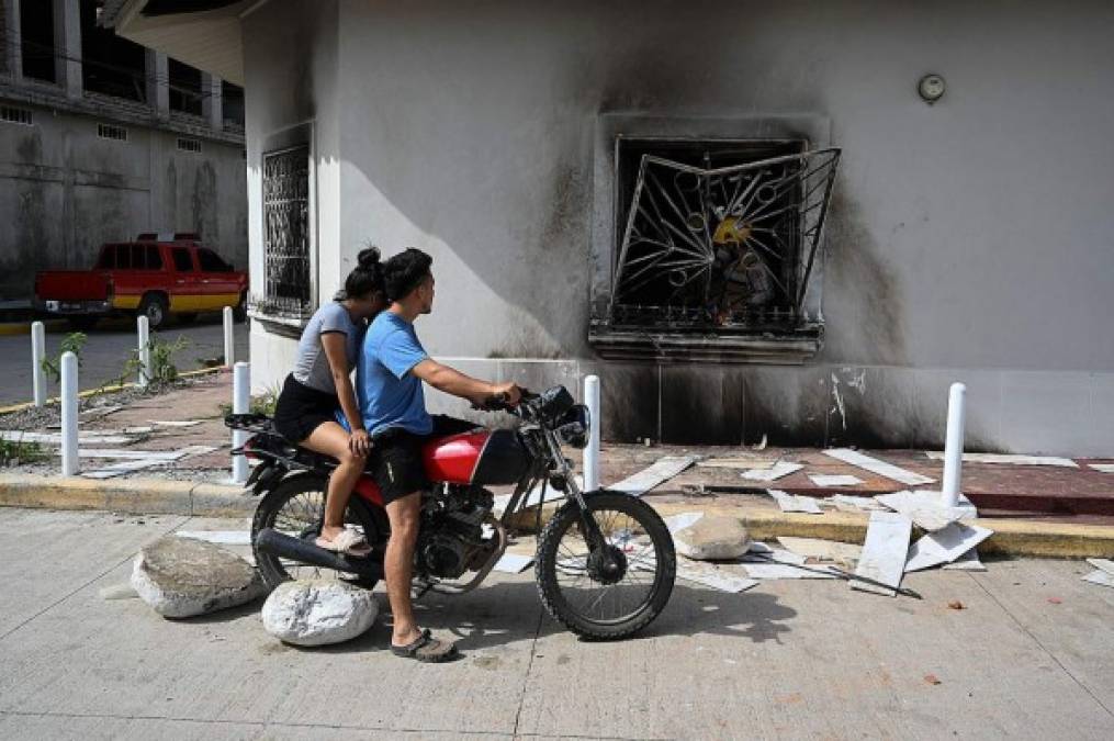 Una pareja pasa por la casa quemada del ciudadano italiano Giorgio Scanu un día después que lo mataran. AFP