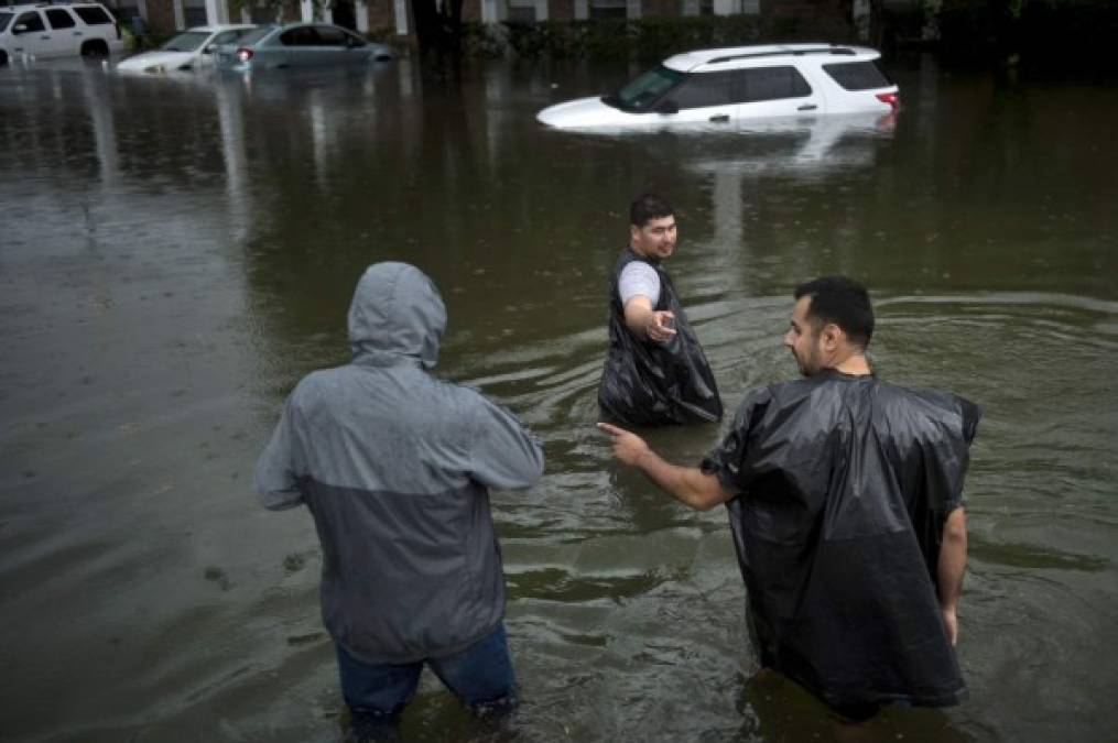 Residentes de Houstos Texas se ayudan unos a otras en una zona inundada.