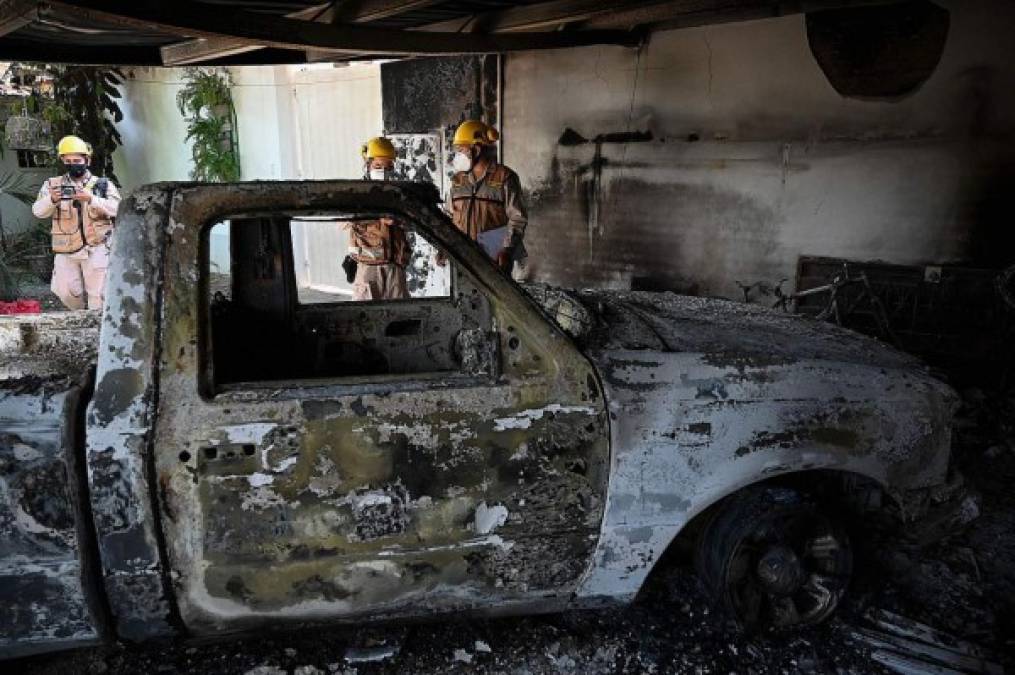 Se observa un auto quemado mientras los bomberos investigan el incendio provocado en la casa del ciudadano italiano Giorgio Scanu. AFP