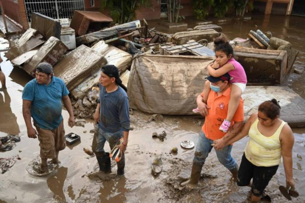 People wade trough a flooded area following the passage of Hurricane Eta in the municipality of Villanueva, department of Cortes, Honduras following on November 7, 2020. - Scores of people have died or remain unaccounted for as the remnants of Hurricane Eta unleashed floods and triggered landslides on its deadly march across Central America. (Photo by Orlando SIERRA / AFP)