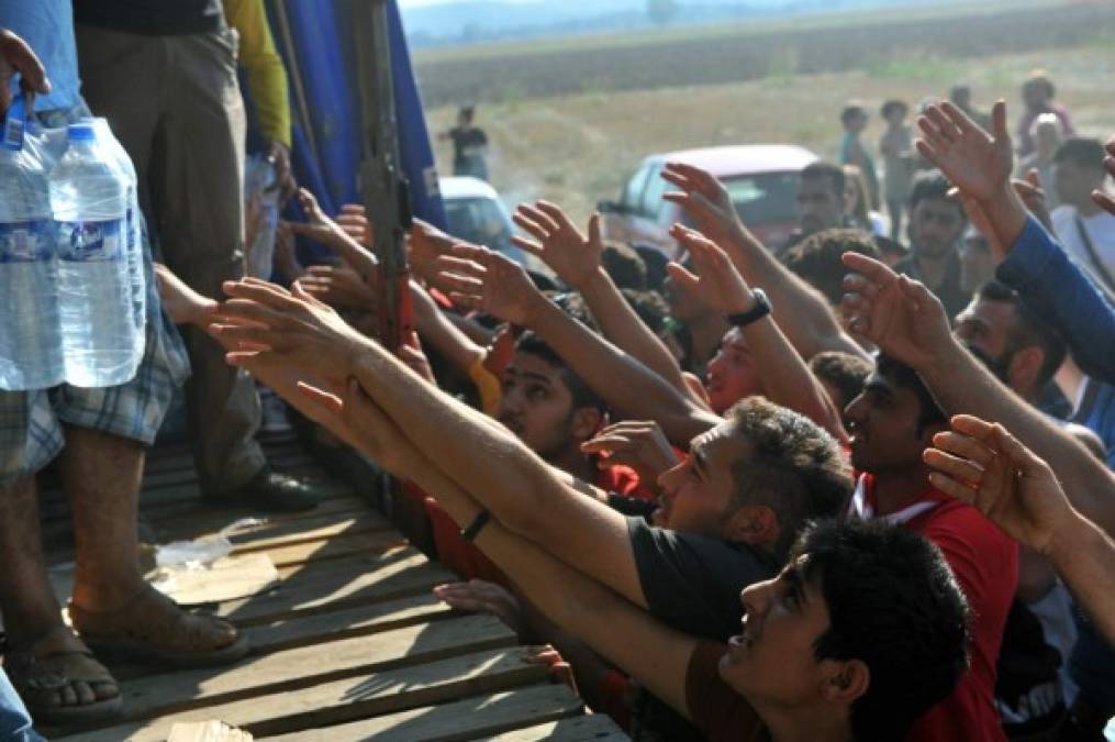 Crisis migratoria. Decenas de migrantes intentan atrapar botellas con agua dadas por voluntarias de organizaciones humanitarias en Grecia. Miles de migrantes han llegado a este país buscando cruzar a Europa para huir de los conflictos en Siria e Irak.