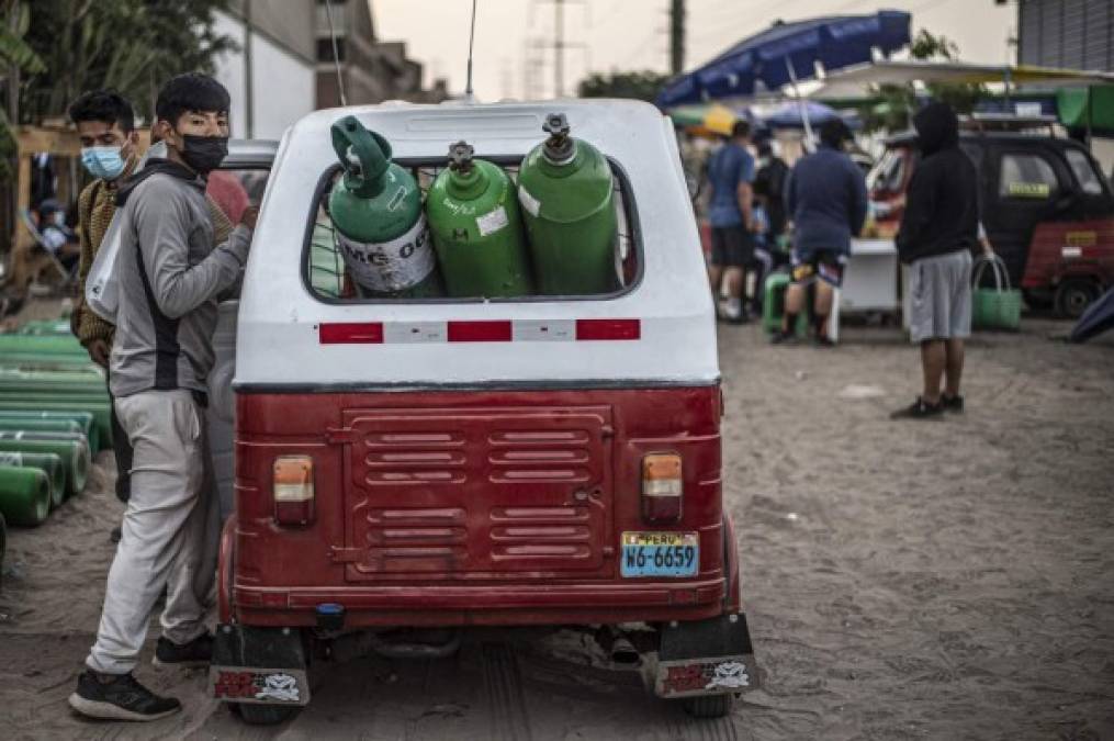 Hombres llegan a hacer cola para recargar los tanques de oxígeno vacíos en Villa El Salvador, en la periferia sur de Lima, el 11 de abril de 2021 (Foto de ERNESTO BENAVIDES / AFP)