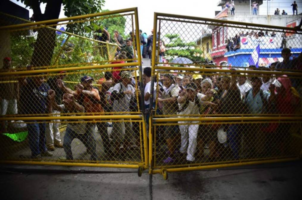 Los hondureños también lograron abrir y doblar un portón metálico que impedía el paso hacia la frontera. Foto AFP