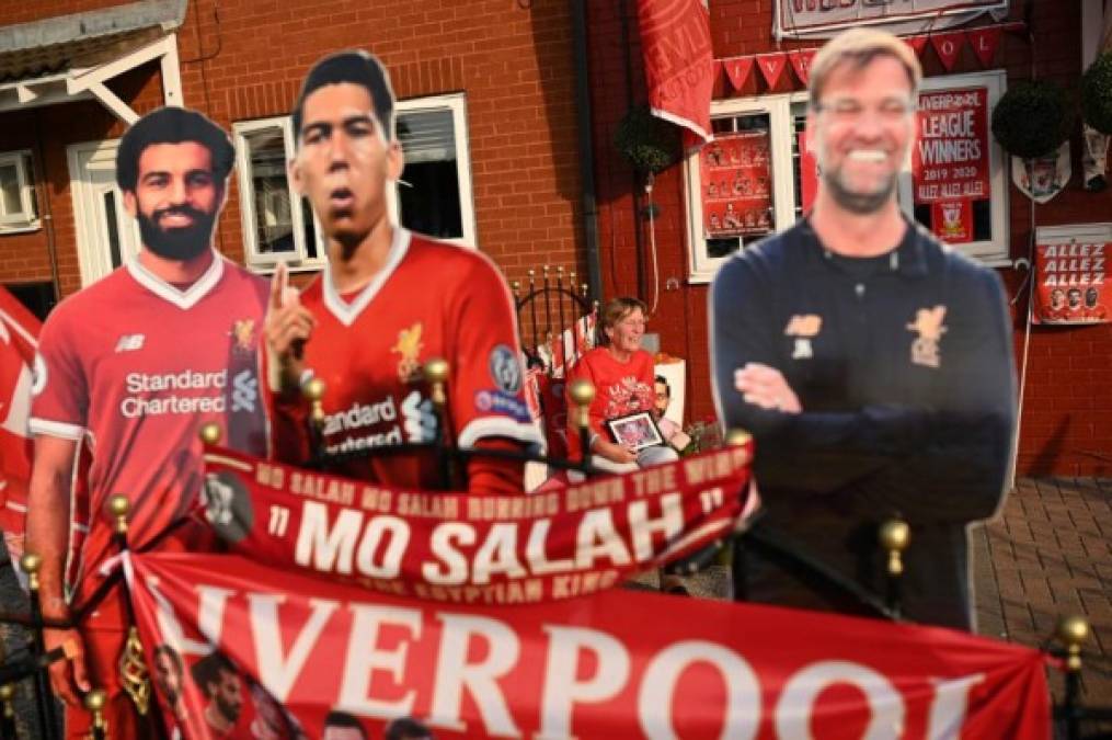 Liverpool fan Emily Farley sits outside her home, decorated with Liverpool banners and cut outs, in Liverpool, north west England on June 25, 2020, as she waits for the result of the match between Manchester City and Chelsea, which gives Liverpool the possibility of taking the Premier League championship. (Photo by Oli SCARFF / AFP) / RESTRICTED TO EDITORIAL USE. No use with unauthorized audio, video, data, fixture lists, club/league logos or 'live' services. Online in-match use limited to 120 images. An additional 40 images may be used in extra time. No video emulation. Social media in-match use limited to 120 images. An additional 40 images may be used in extra time. No use in betting publications, games or single club/league/player publications. /