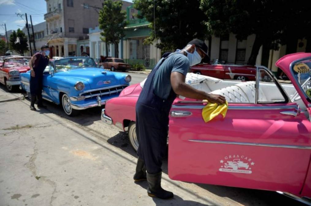 Los trabajadores de una compañía privada de taxis desinfectan los viejos automóviles estadounidenses con máscaras faciales como medida preventiva contra la propagación del nuevo coronavirus, en La Habana, Cuba. Foto EFE